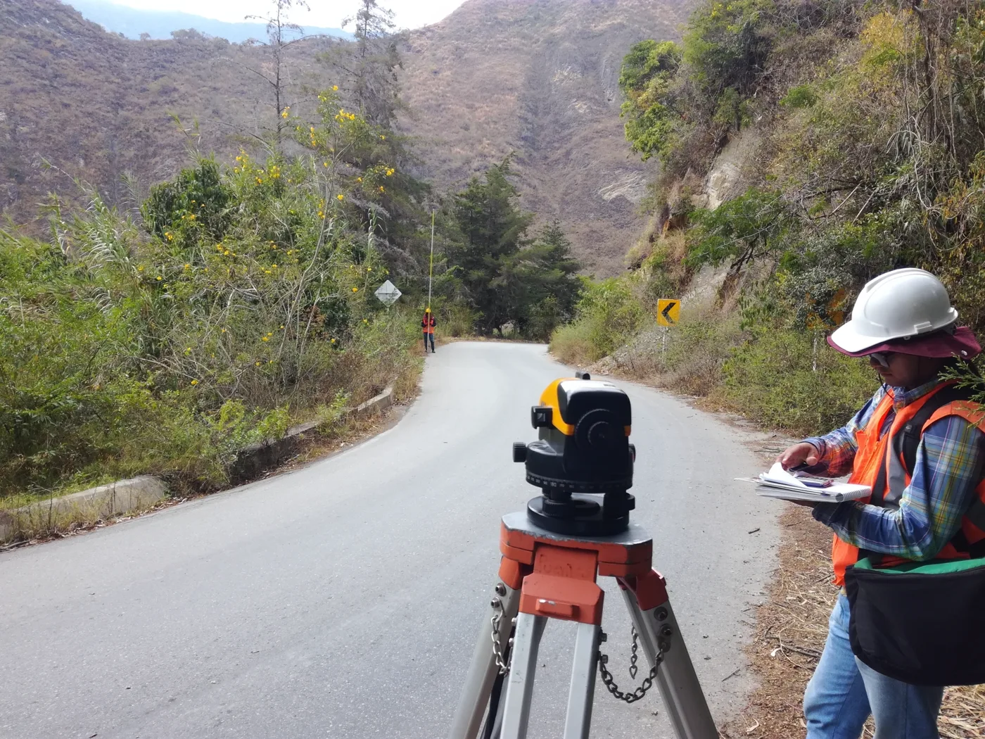 Topógrafa con nivel tomando medidas en una vía de montaña