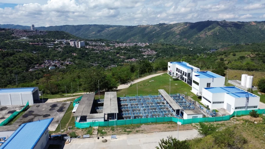 Vista aérea de una planta de tratamiento de agua potable terminada, con la ciudad al fondo