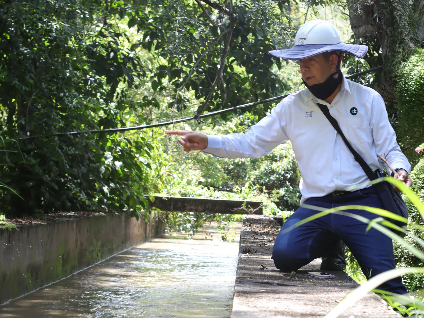 Ingeniero de 5T midiendo el caudal de un canal de agua entre la vegetación